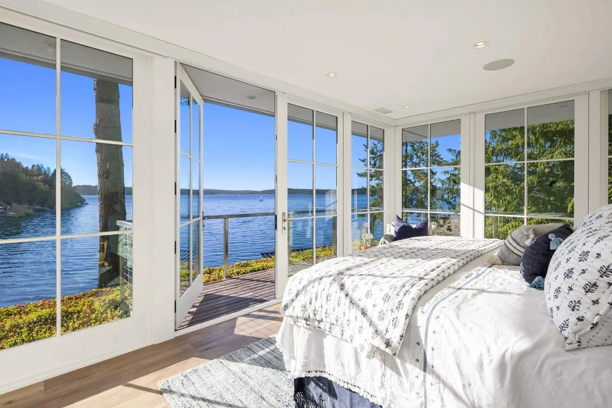 Waterfront bedroom with floor-to-ceiling grid windows and direct outdoor access in the Lafayette House.