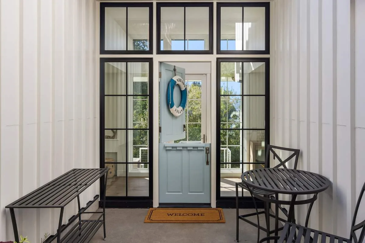 The Lafayette House features a covered entry porch with a blue Dutch door and large black-framed sidelights and transom windows.