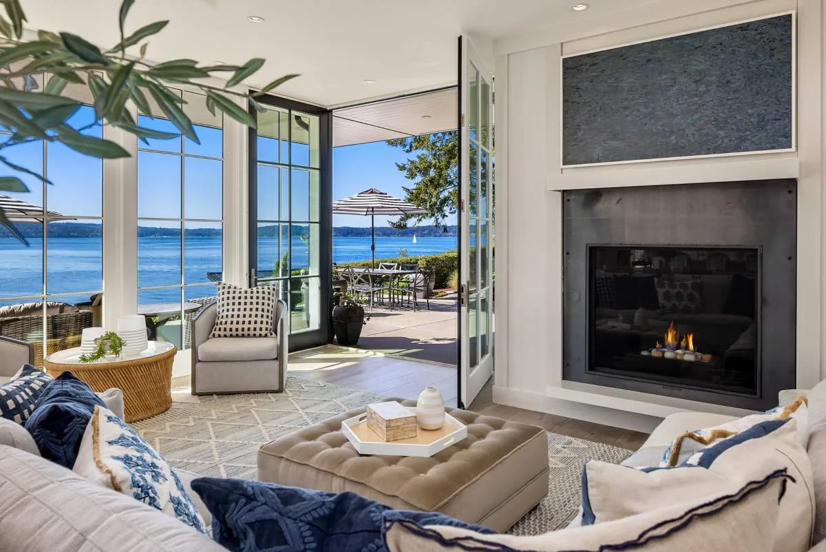 The Lafayette House living room opens to a patio with a water view and includes a modern fireplace.