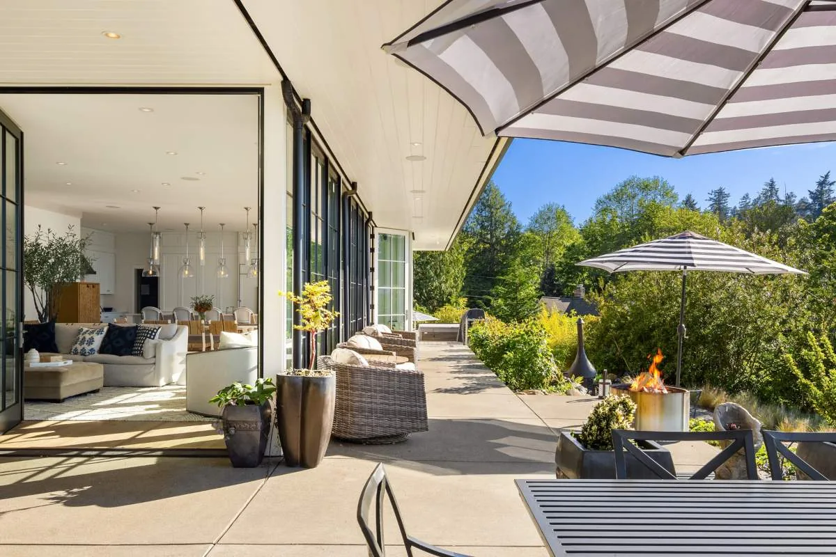 The Lafayette House features a covered concrete patio with wicker chairs and black-framed folding doors connecting to the living space.