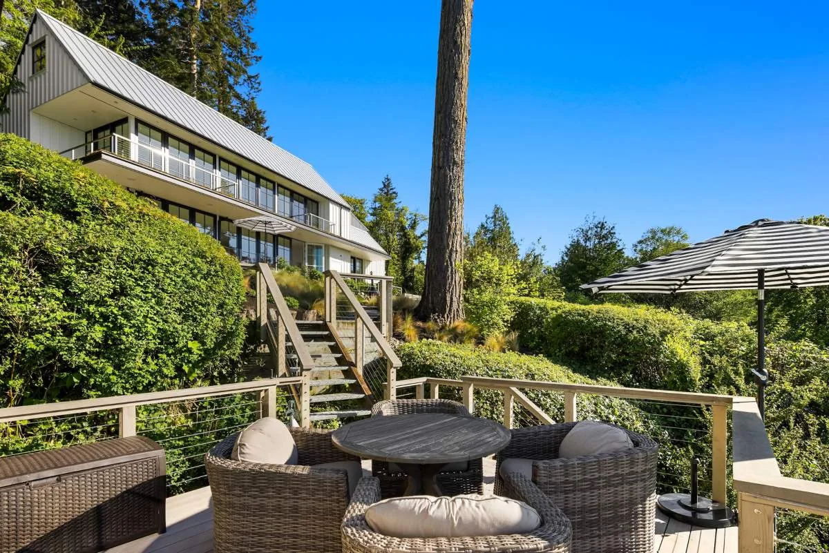 Outdoor living space featuring wicker chairs and a striped umbrella at Lafayette House by BC&J Architects.