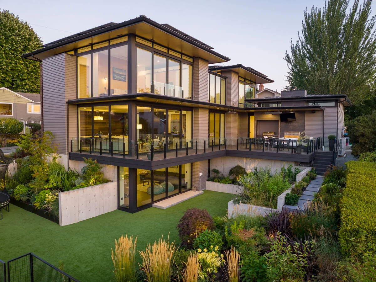 West Seattle House features modern design with extensive glazing, wood siding, and a landscaped garden on a sloped site.
