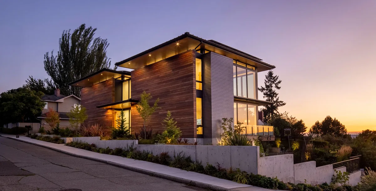 The West Seattle House by BC&J Architects features wood siding and expansive glazing on a hillside lot.