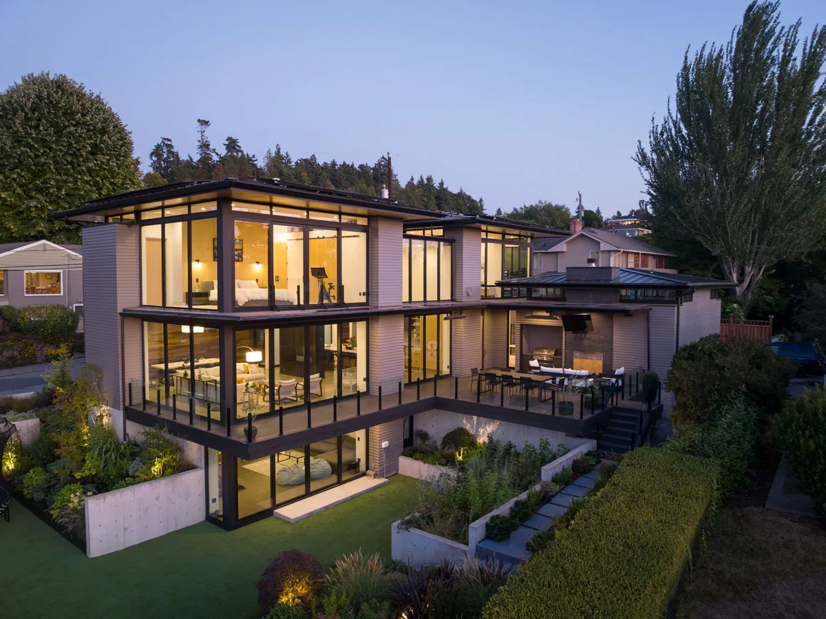 West Seattle House features extensive glazing, a multi-level outdoor terrace, and landscaped garden on a sloped site.