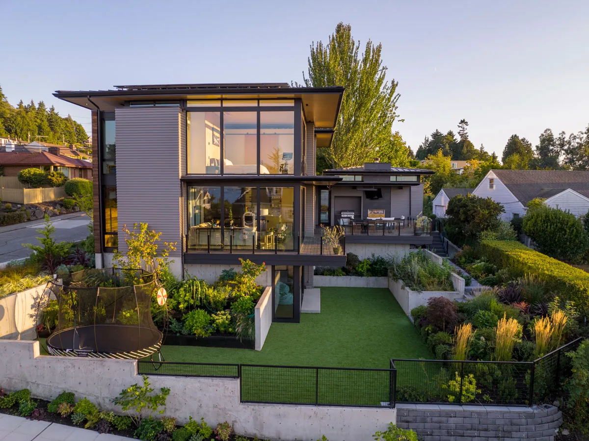 West Seattle House features a modern design with large floor-to-ceiling windows and a landscaped garden with concrete retaining walls.