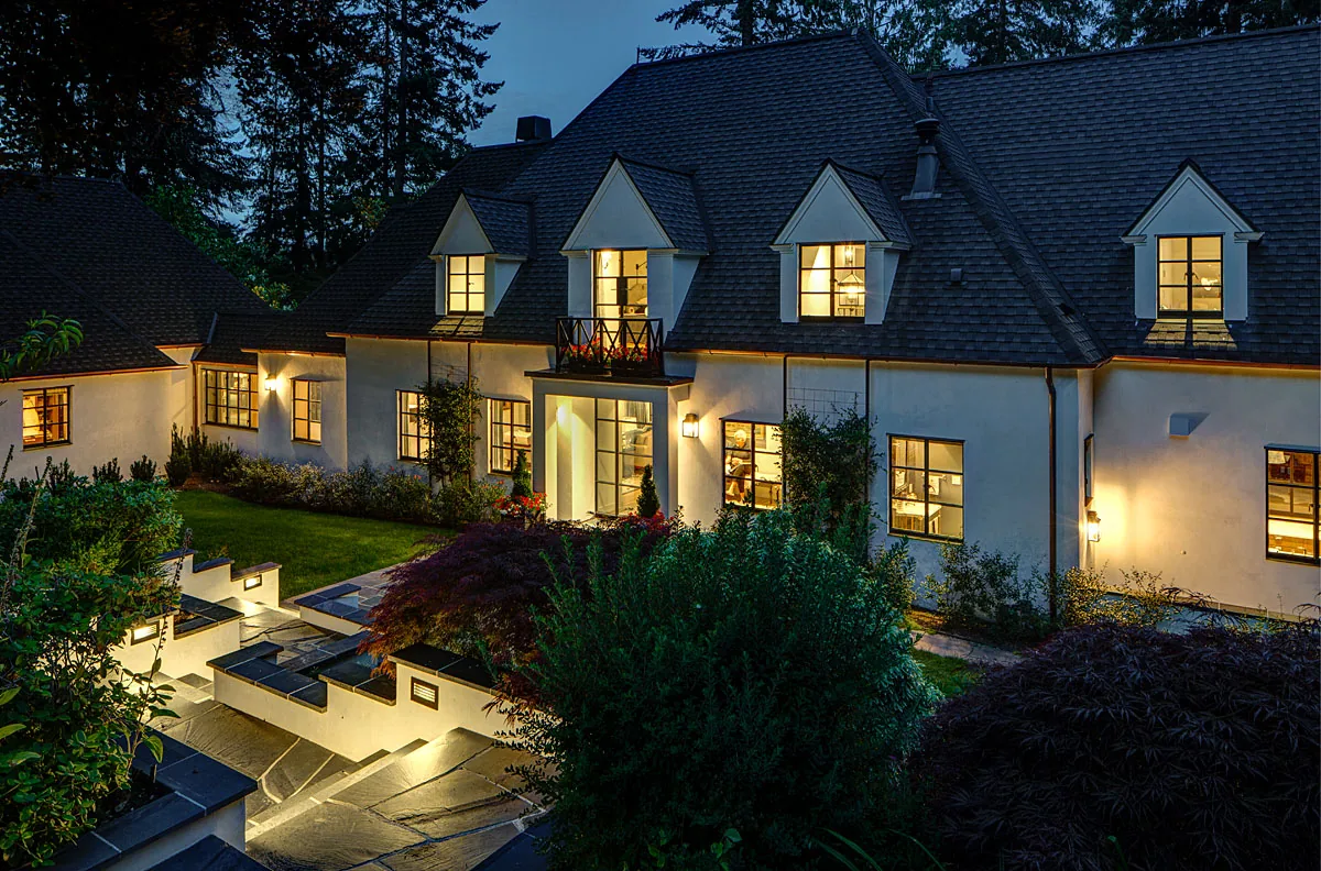 Manzanita Bay House features a steep pitched roof with dormer windows and a landscaped yard with stone steps and flower boxes.
