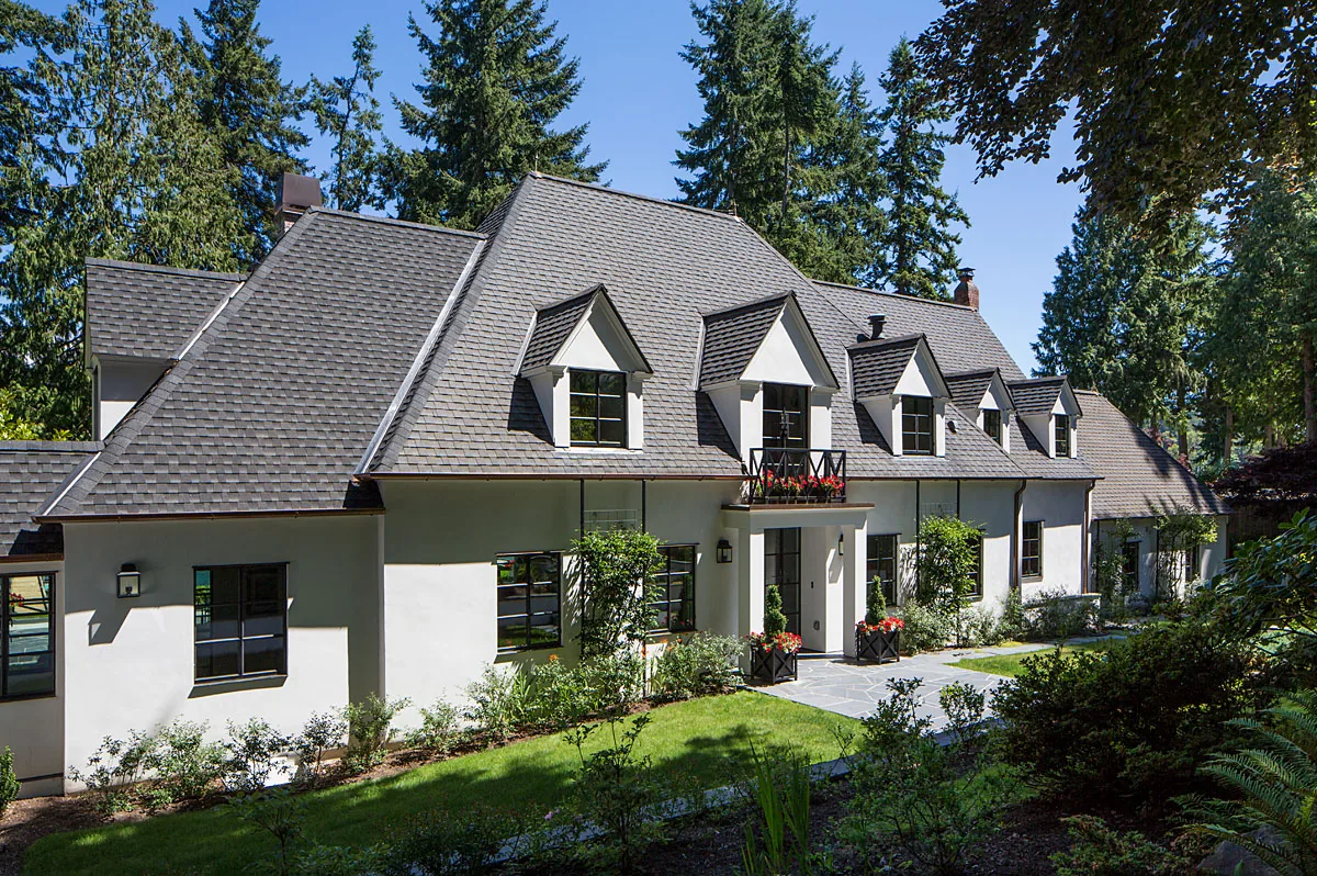 Manzanita Bay House features steep pitched roof with dormer windows and a landscaped front yard with stone steps.