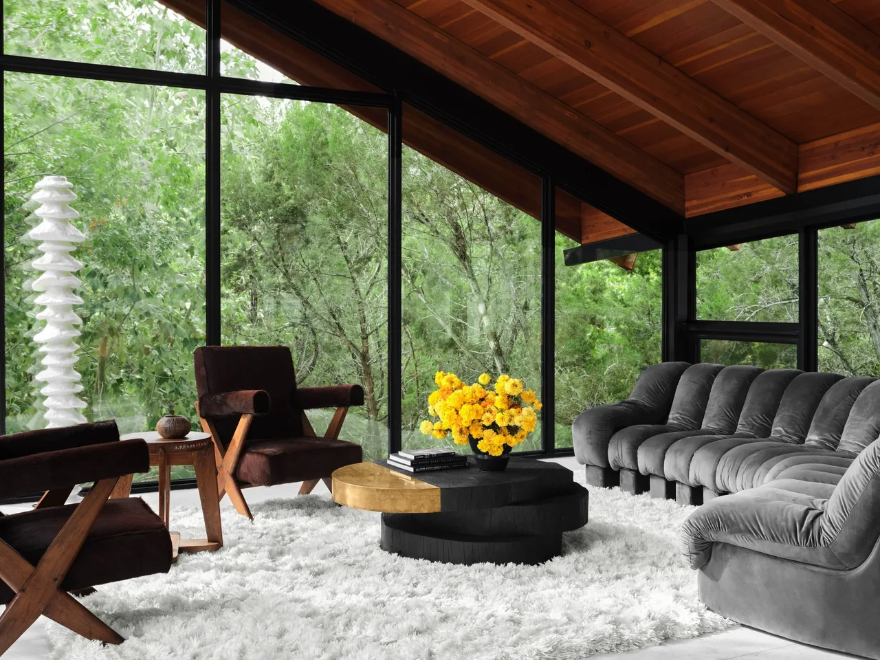 Living room in Falling Leaves House with floor-to-ceiling glazing and wood ceiling with exposed beams.