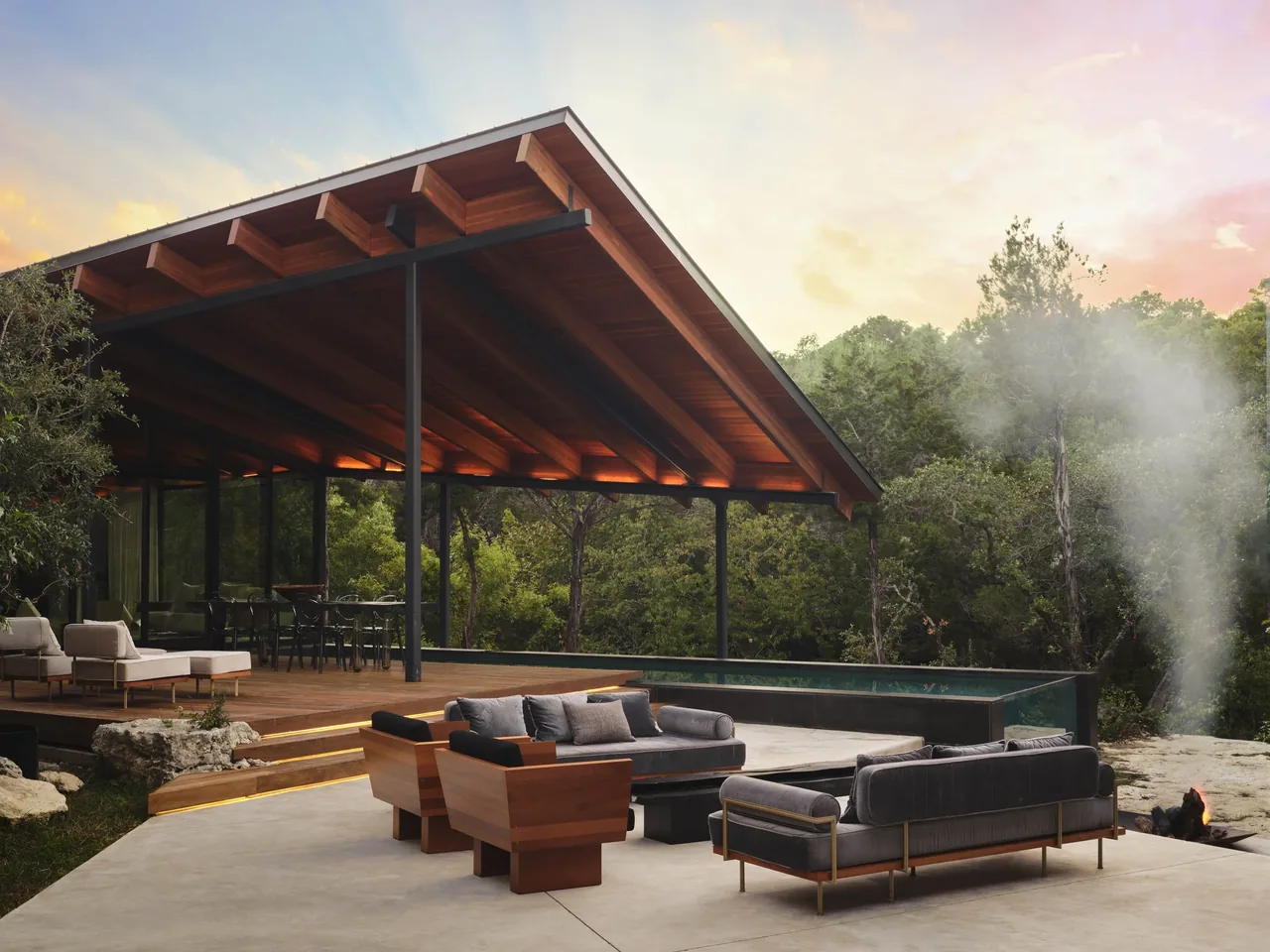 The Falling Leaves House features an elevated covered patio with wood soffit and black steel columns overlooking a pool with a transparent glass wall.