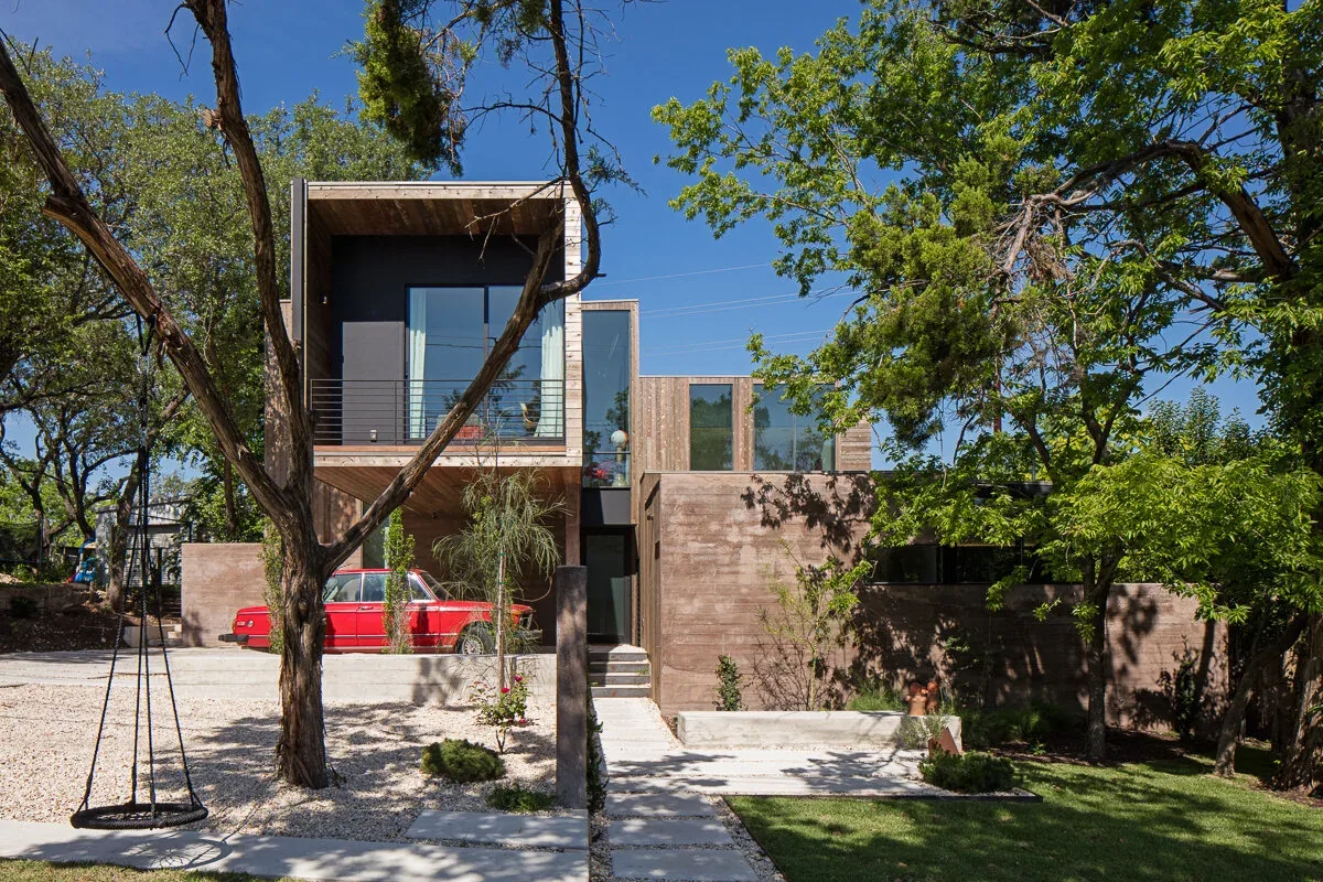 Edgeland House by Bercy Chen Studio features concrete and vertical wood siding with large windows and a landscaped front yard.