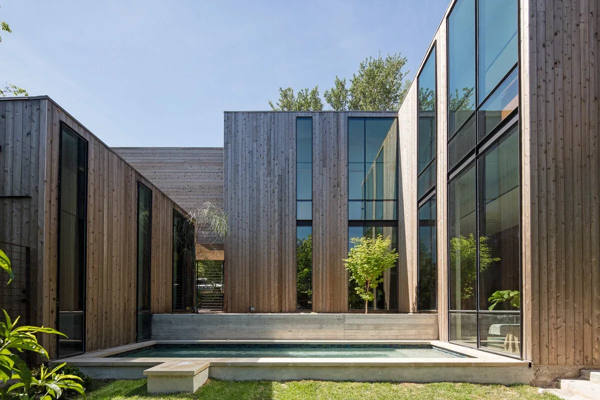 Edgeland House courtyard features vertical wood siding, large glass windows, and a concrete-bordered pool.