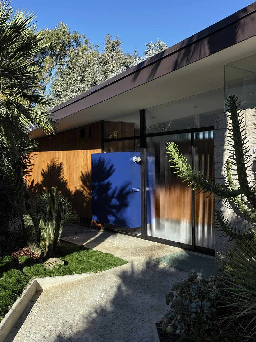 Modern entry of Baldwin Hills Vista project by Bestor Architecture features a distinctive blue door and mixed material facade.
