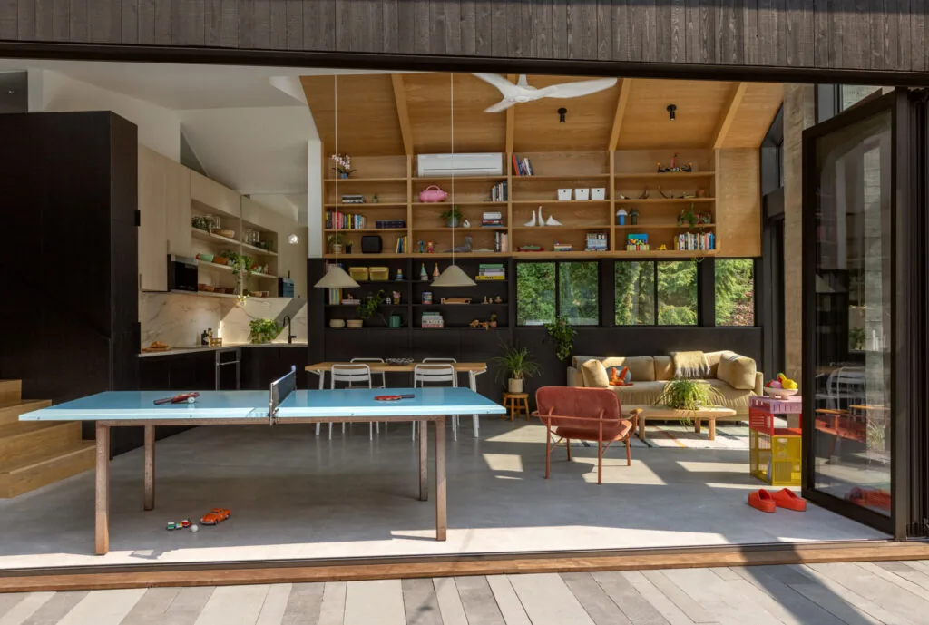Living space with wood vaulted ceiling, black window frames, and an adjacent kitchen area with light wood cabinetry at Park Pad.