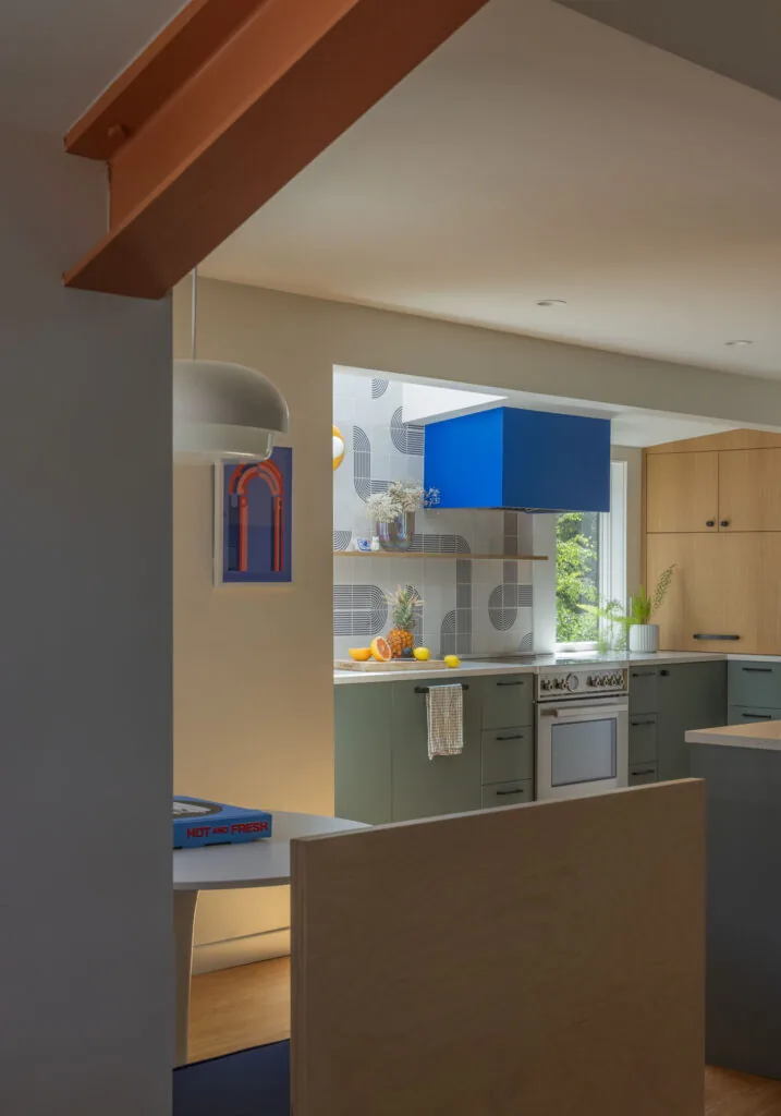Modern kitchen featuring blue range hood, olive green lower cabinetry, and geometric tile backsplash.