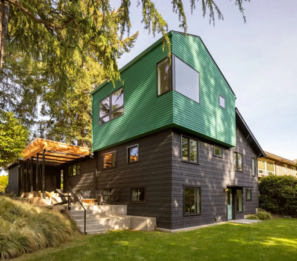 The Chez Shay residential project features black shingle siding with a green clad upper story and a covered patio.