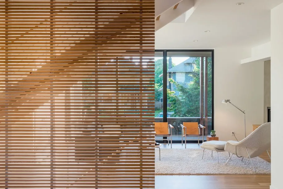 Living room in Capitol Hill Residence features a wooden slat partition and sliding glass doors with black frames.