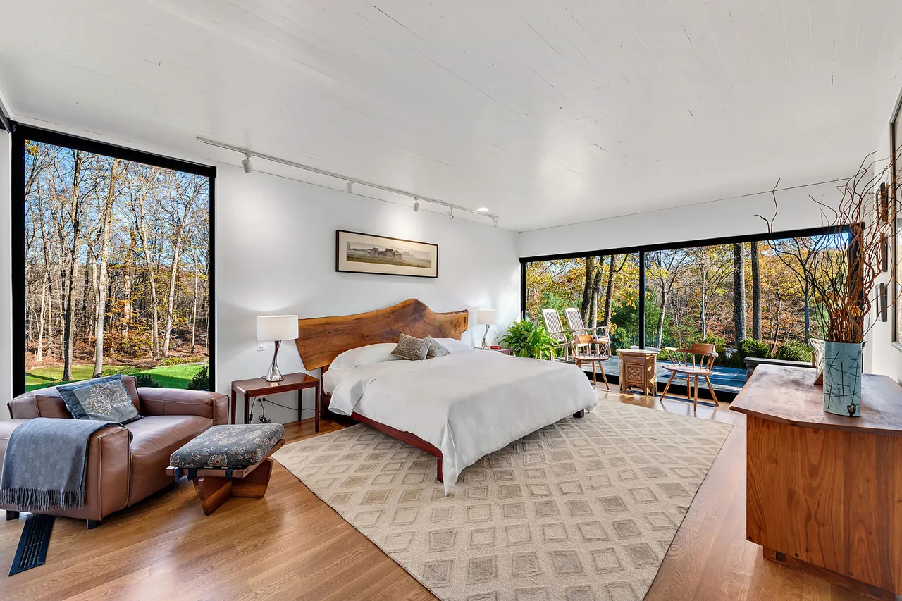 Bedroom with floor-to-ceiling glazing on two walls and a wood slab headboard at Stockwell-Rodríguez Residence by Belmont Freeman Architects.