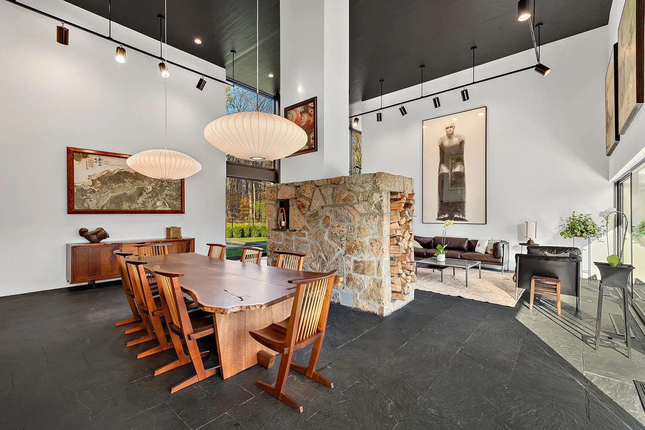 The Stockwell-Rodríguez Residence includes a dining area with a large wooden table and a living space with modern artwork, centered around a stone fireplace.