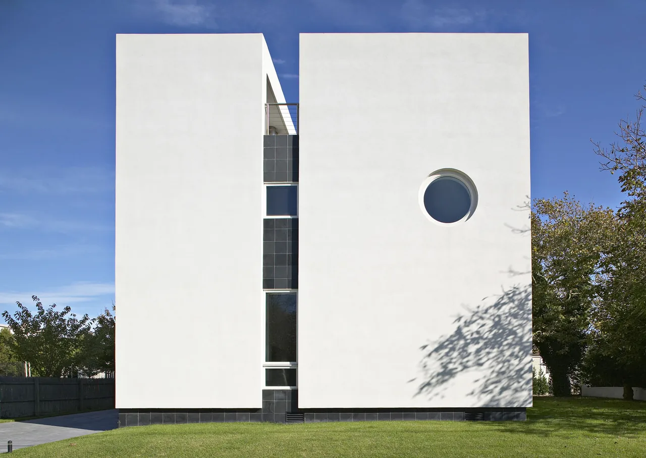 Kowalewski Residence by Belmont Freeman Architects features a white stucco exterior with a circular porthole window and vertical window strip.