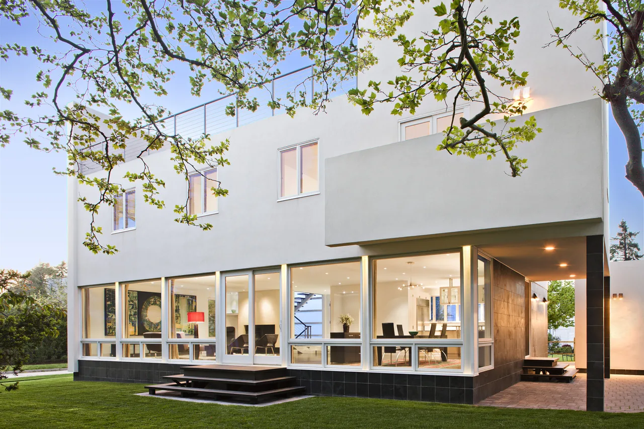 Kowalewski Residence by Belmont Freeman Architects features large ground-floor windows and a covered patio area.