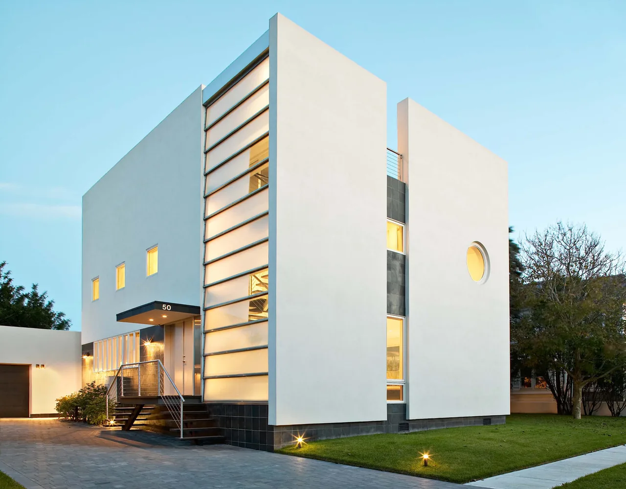 The Kowalewski Residence features a white cubic form with a vertical window strip and a circular porthole window on the facade.