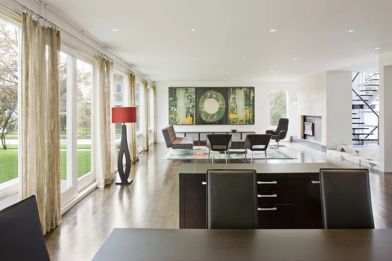 The Kowalewski residence living room features floor-to-ceiling windows and a linear fireplace adjacent to floating stairs.
