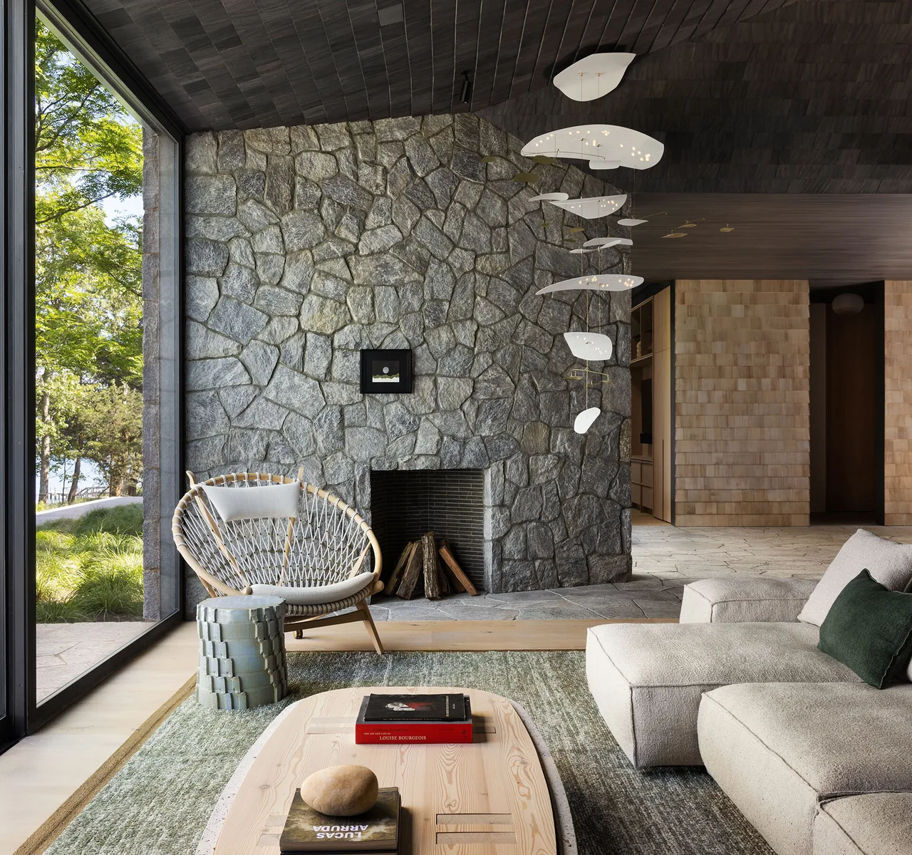 Sag Harbor Bay living room features a stone fireplace wall and floor-to-ceiling window overlooking a garden.
