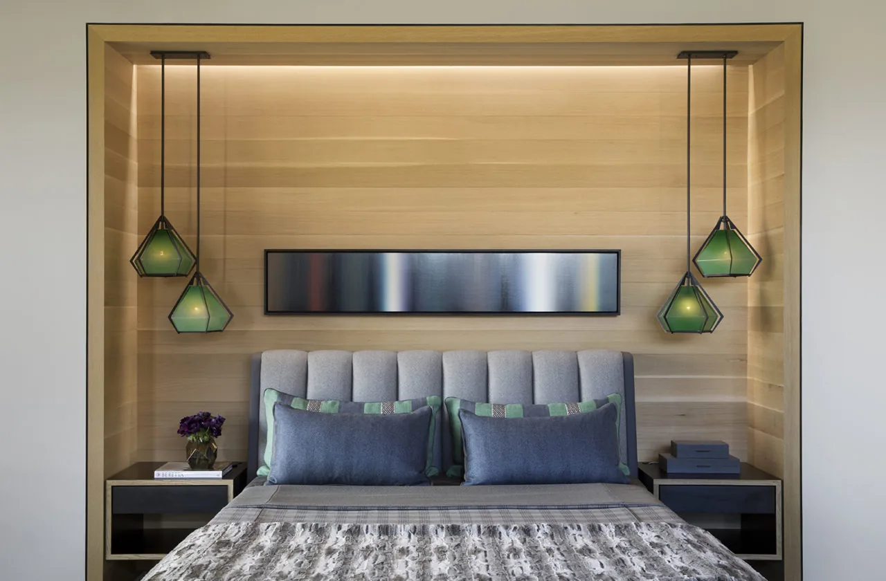 Modern bedroom with tufted bed, light wood paneling, and geometric pendant lights creating a calming atmosphere.