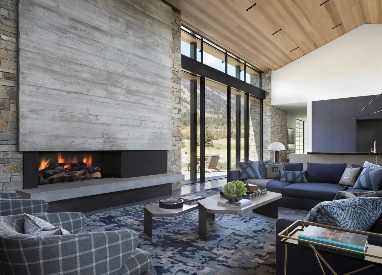 Living room in Shooting Star project with concrete fireplace and floor-to-ceiling glazing offering mountain views.