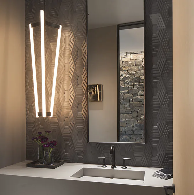Bathroom interior features dark hexagonal patterned tiles, a rectangular sink, and a vertical modern light fixture.