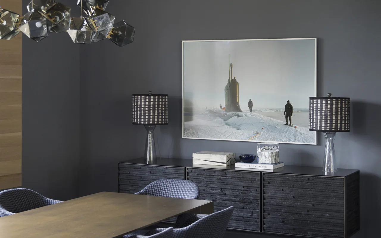 Dining room features a dark textured sideboard with lamps and photo artwork, centered on a gray wall.