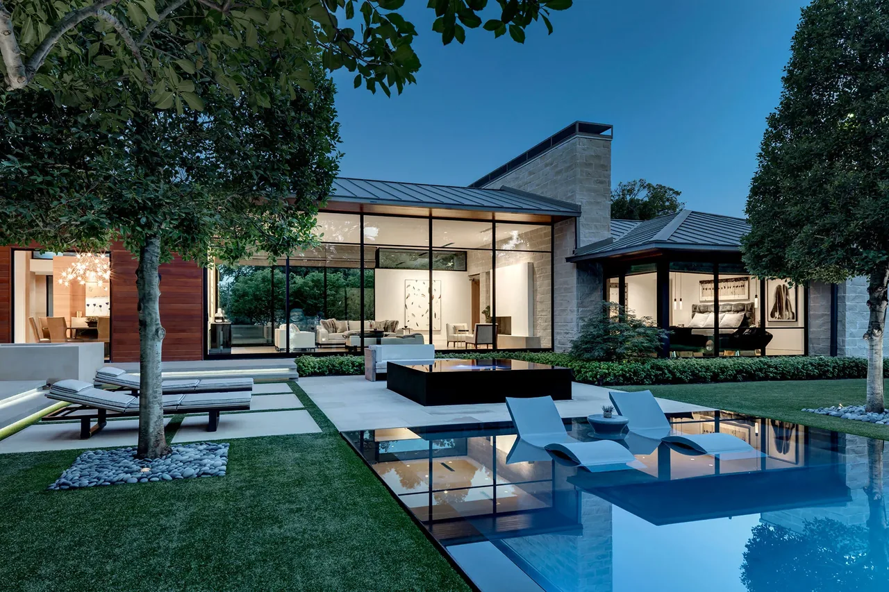 Backyard of the Manning project features a reflective pool, fire pit, and floor-to-ceiling glazing under a standing seam metal roof.