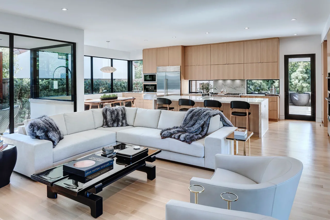 Open-plan living and kitchen area with light wood floors and black window frames in the Manning project.