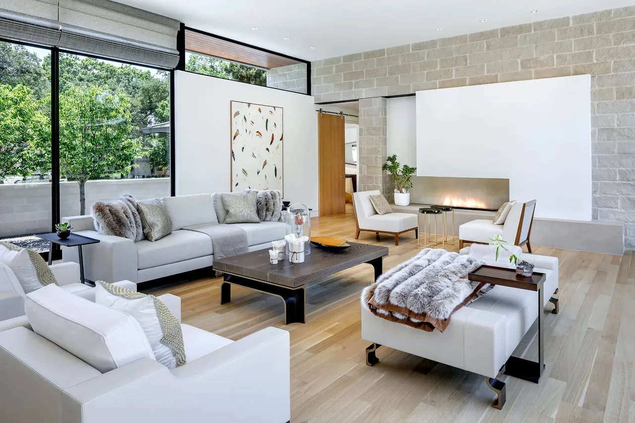 Living room featuring white sofas, floor-to-ceiling glazing, and a linear fireplace with contemporary design.