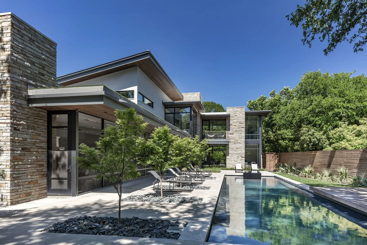 Wildwood I features modern design with stone and glass exterior, pool, and outdoor lounge area by BM Architects.