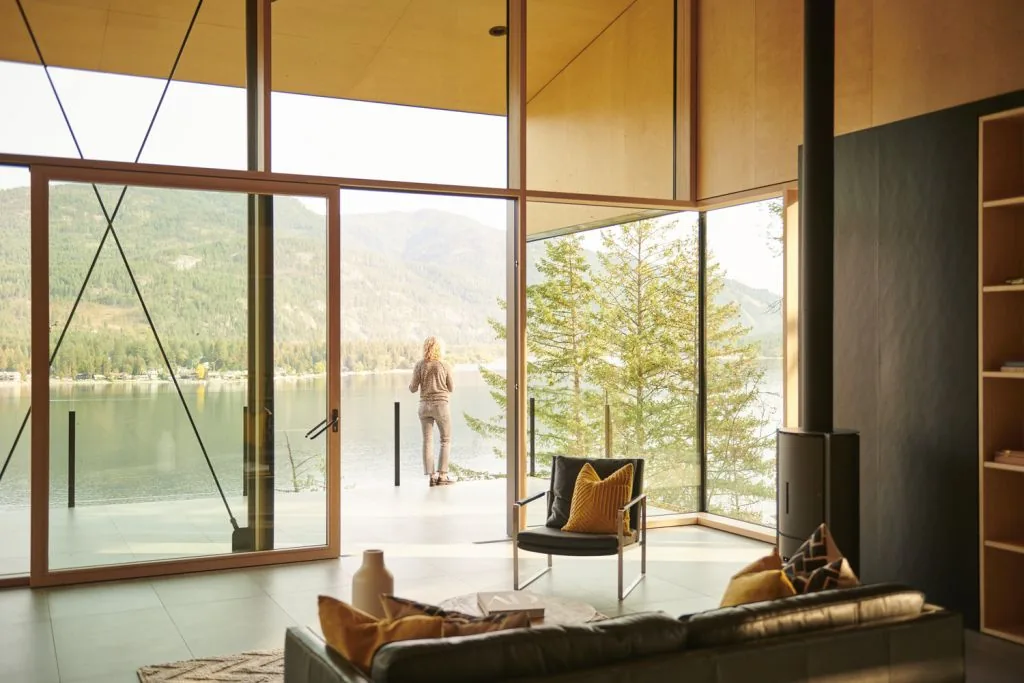 Living room with floor-to-ceiling windows providing expansive lake and forest views.
