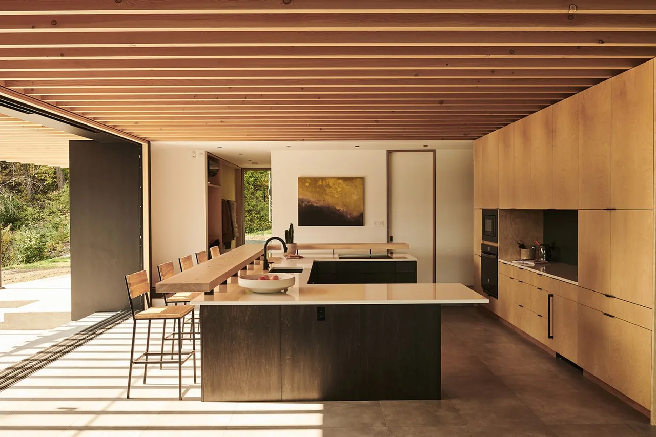 Boundary Point Cabin kitchen features wood ceiling beams, a two-tone island with integrated sink, and high cabinetry.