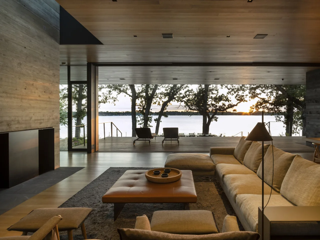 Living area with integrated indoor-outdoor design featuring floor-to-ceiling glazing and wood plank ceiling at the Highbank Residence.