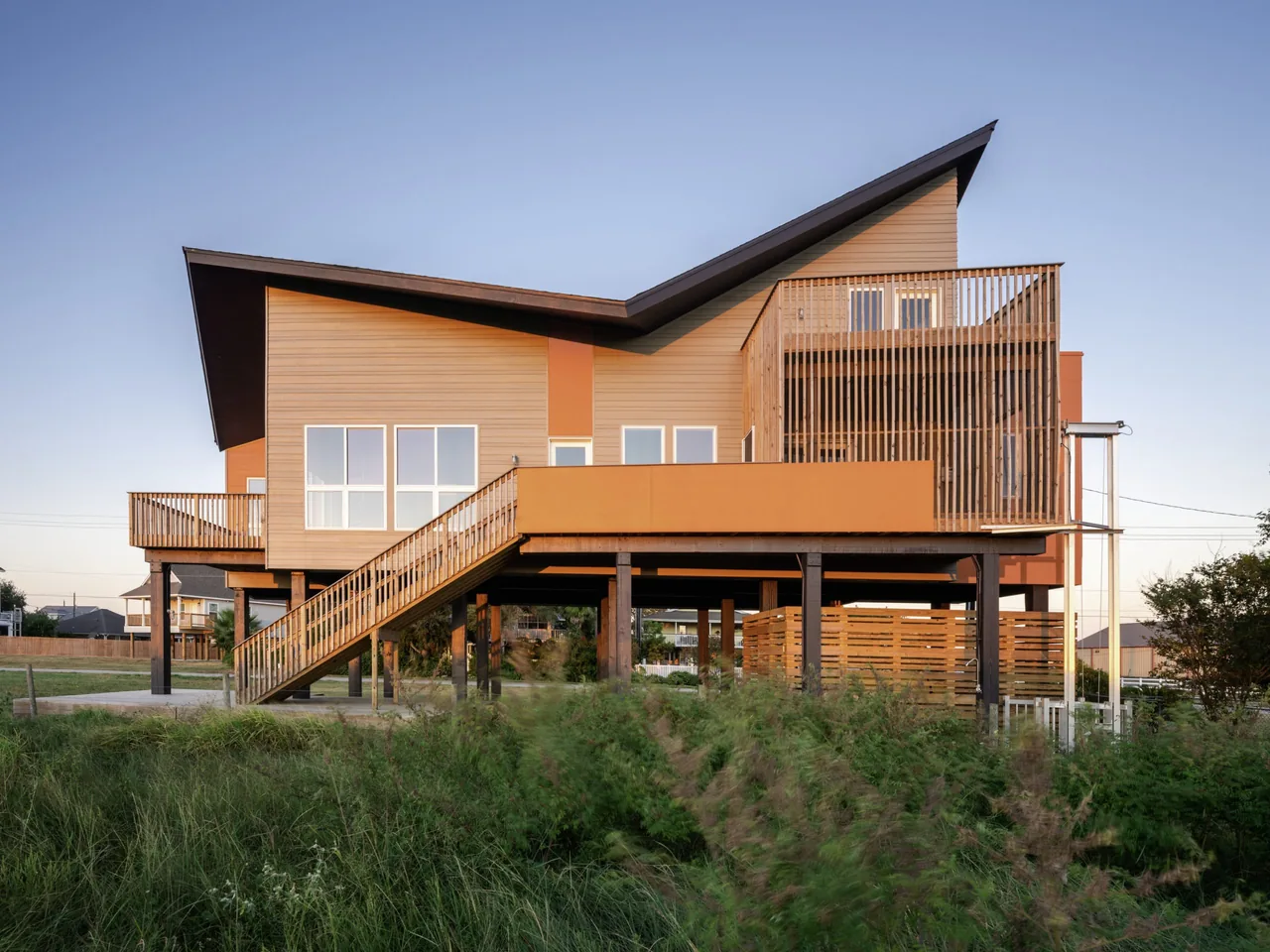 Side exterior of Arnold Beach House showing wood siding, elevated structure, and deck with sloped roof design.