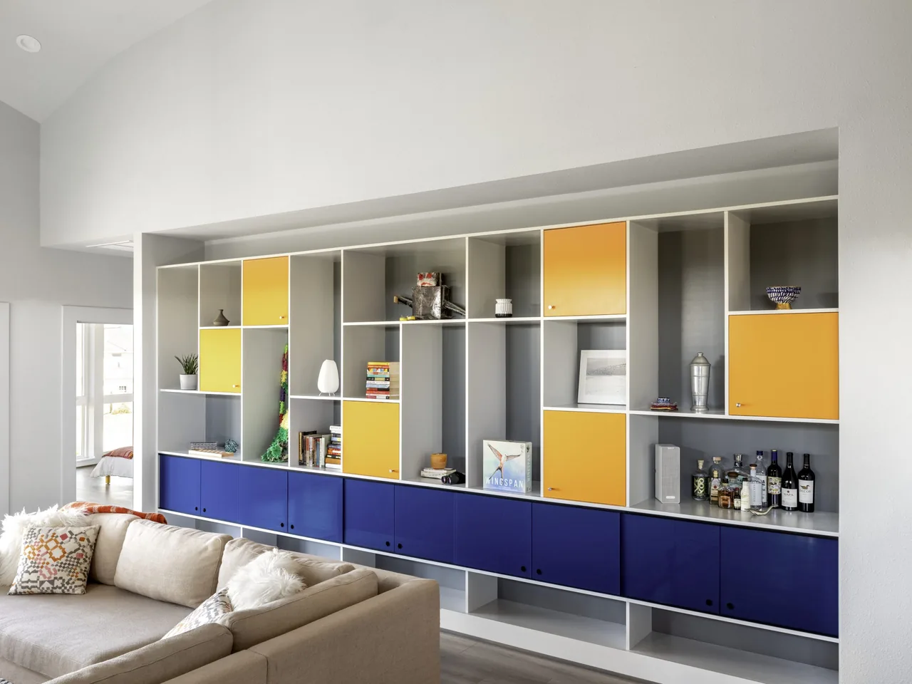 Built-in shelving with colorful yellow and blue cabinets in the Arnold Beach House living room.
