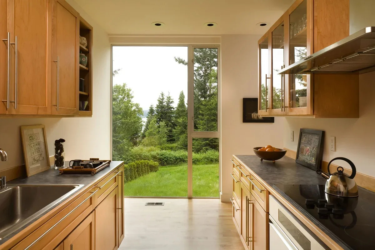 Kitchen with wood cabinets and black countertops featuring a large sliding glass door to the exterior.
