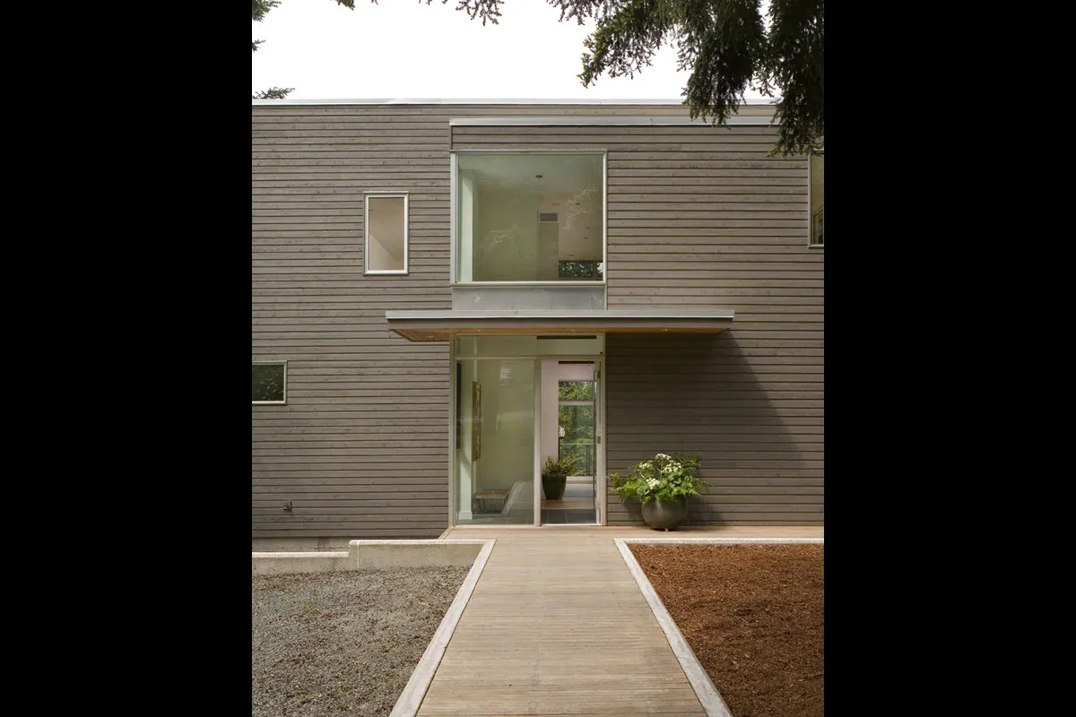 The Geist Residence features horizontal wood siding and large floor-to-ceiling windows at the entrance.