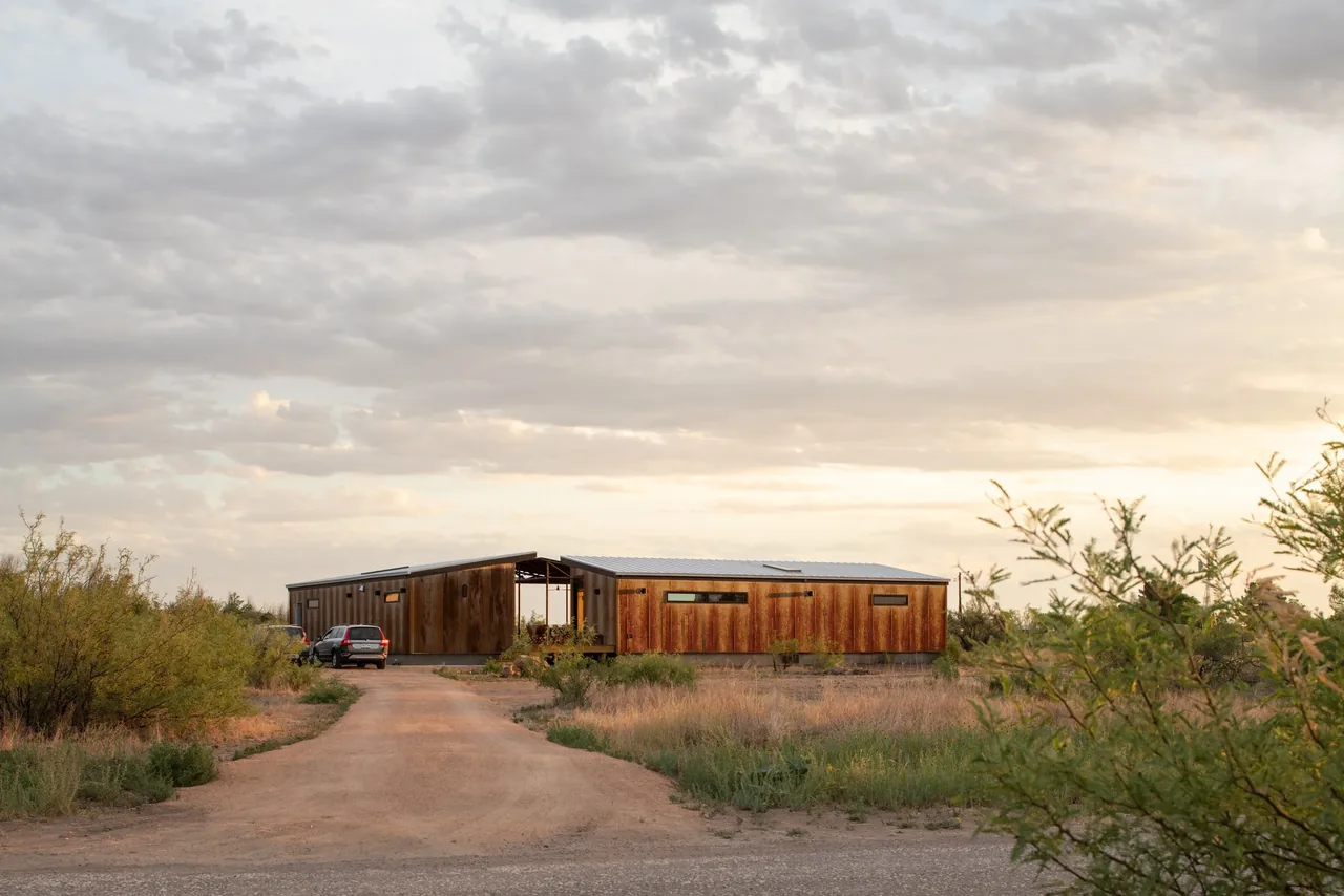 Marfa zFab features two buildings with corrugated siding and shed roofs in a rural setting at sunset.