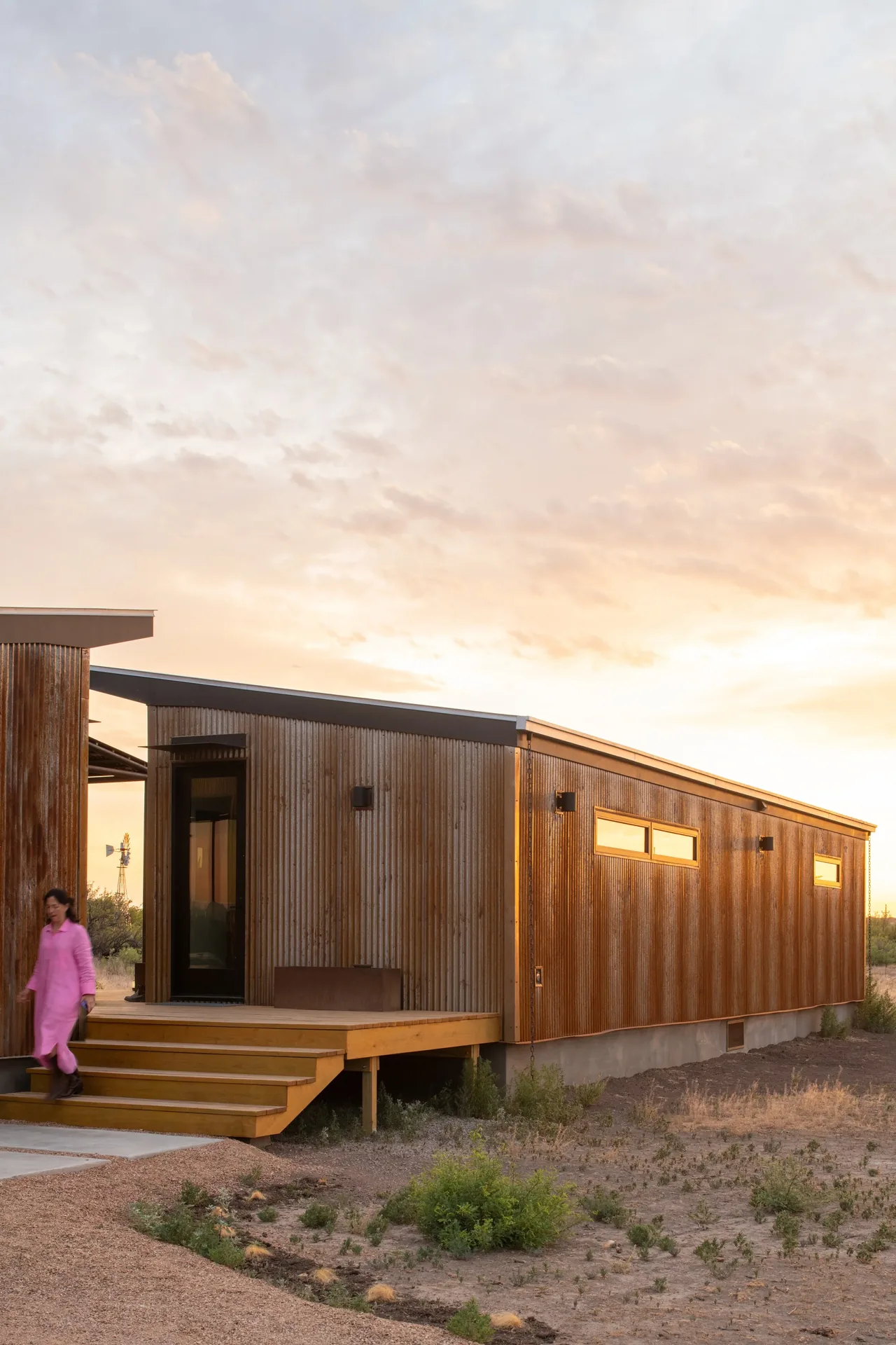 The Marfa zFab project features corrugated wood siding and a shed roof, set in a natural landscape at sunset.
