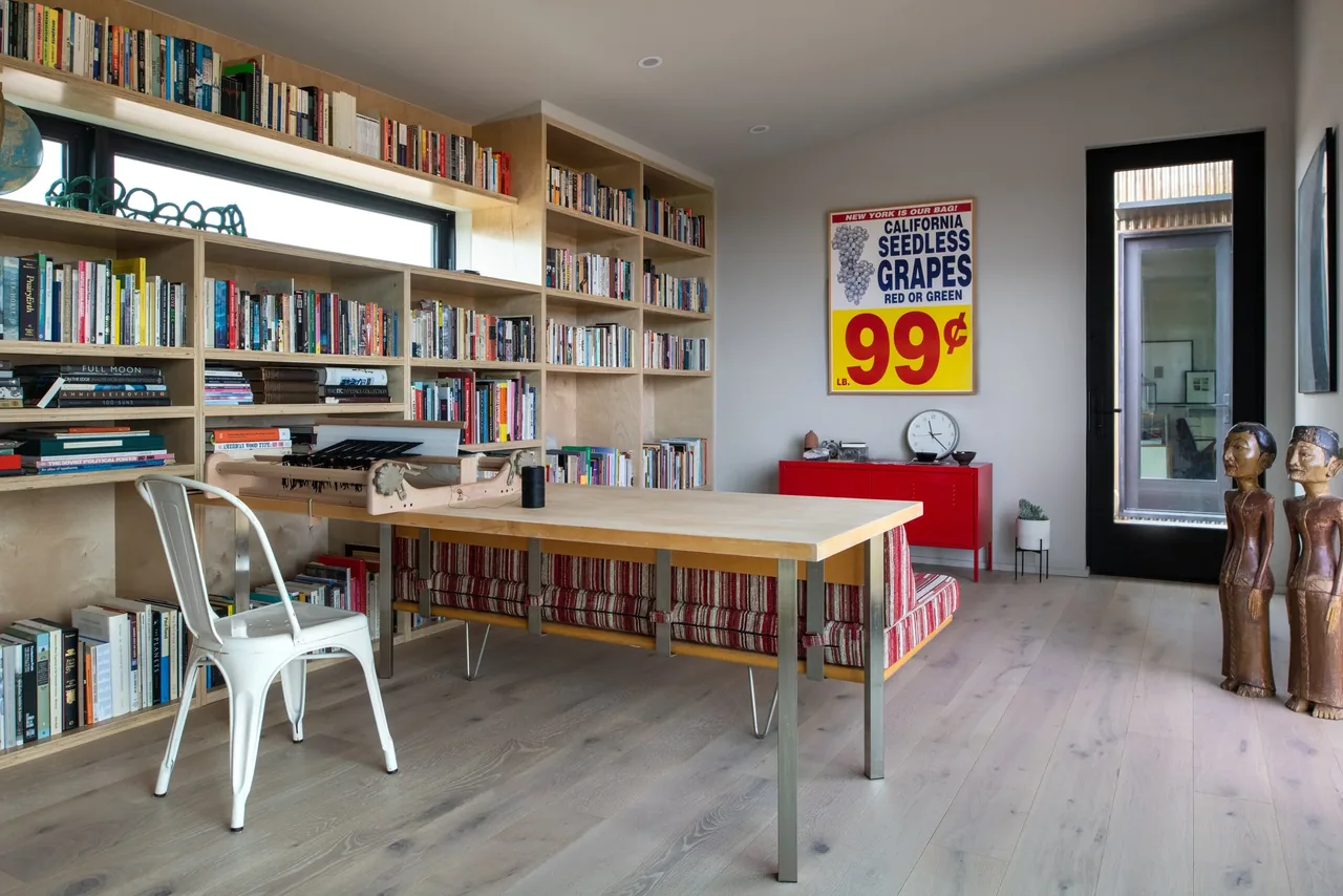 Office with floor-to-ceiling built-in bookshelf, wooden desk, and striped bench seating in a modern style.