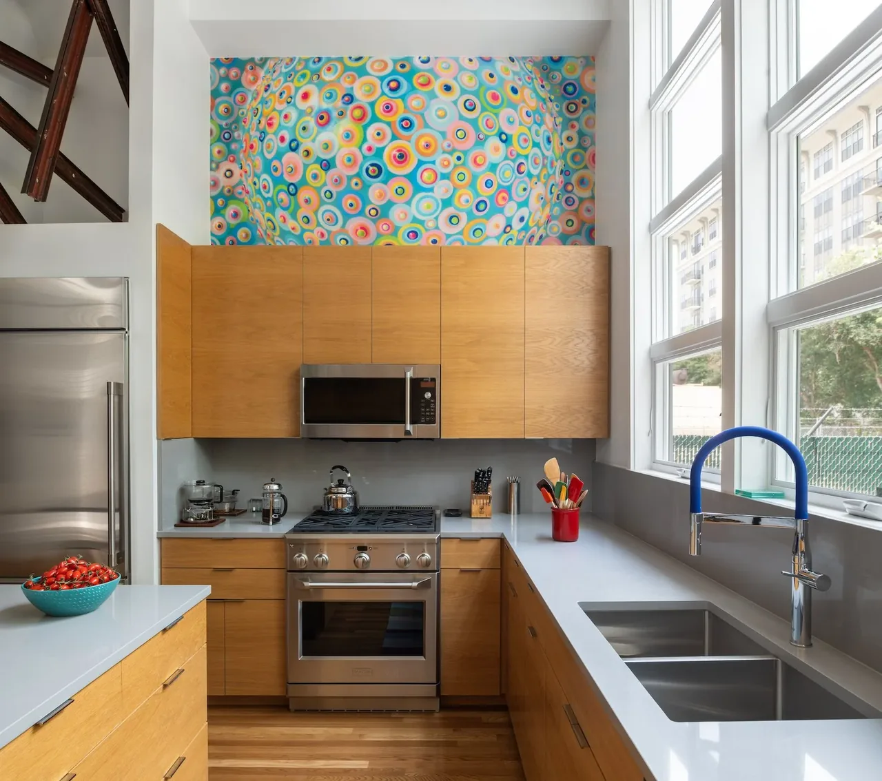 The Pink House kitchen features oak cabinetry, stainless steel appliances, and vibrant circular artwork above the cabinets.