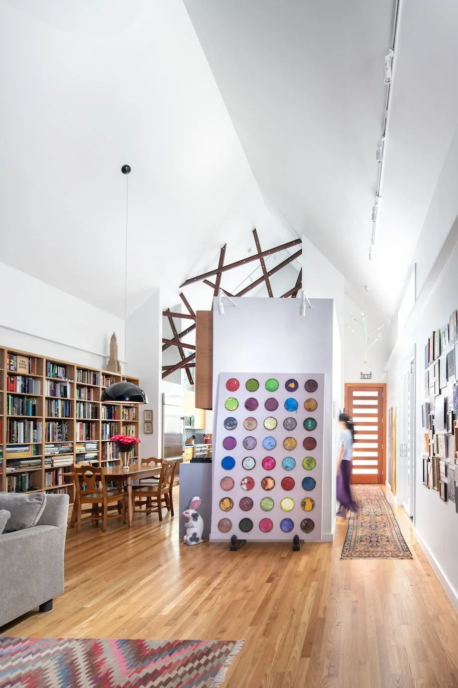 The Pink House features vaulted ceilings with exposed beams and a colorful art piece in the living and dining area.