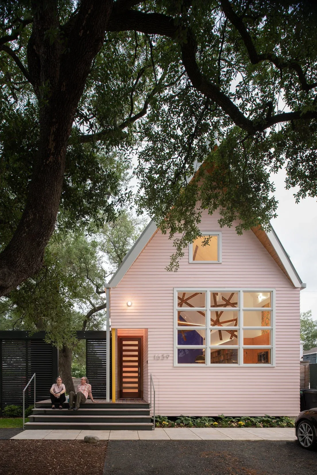 The Pink House features wood siding and a steep gable roof with a large multi-pane window on the front facade.