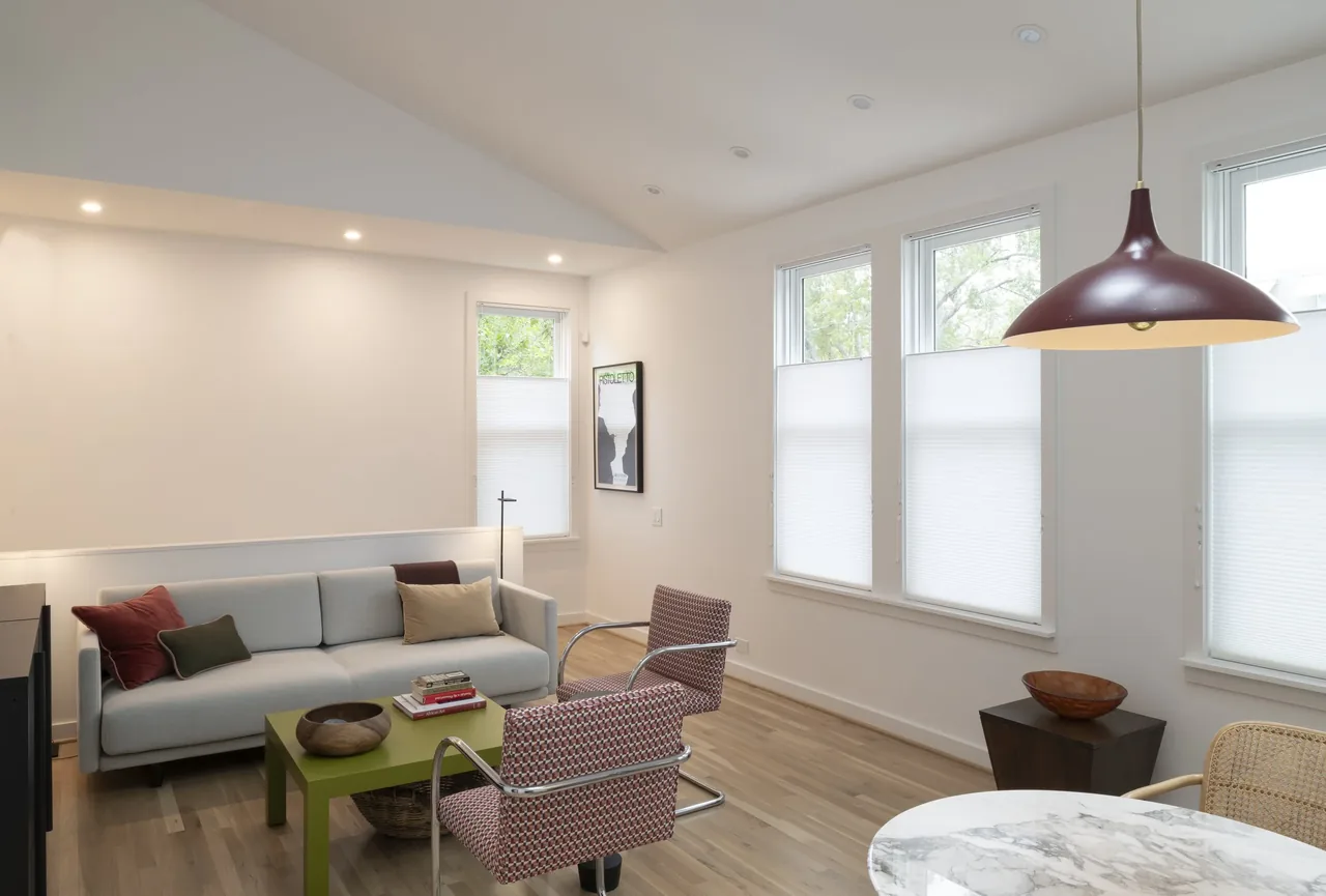 Modern living room with wood flooring, recessed lighting, and a spherical pendant light above a marble table.