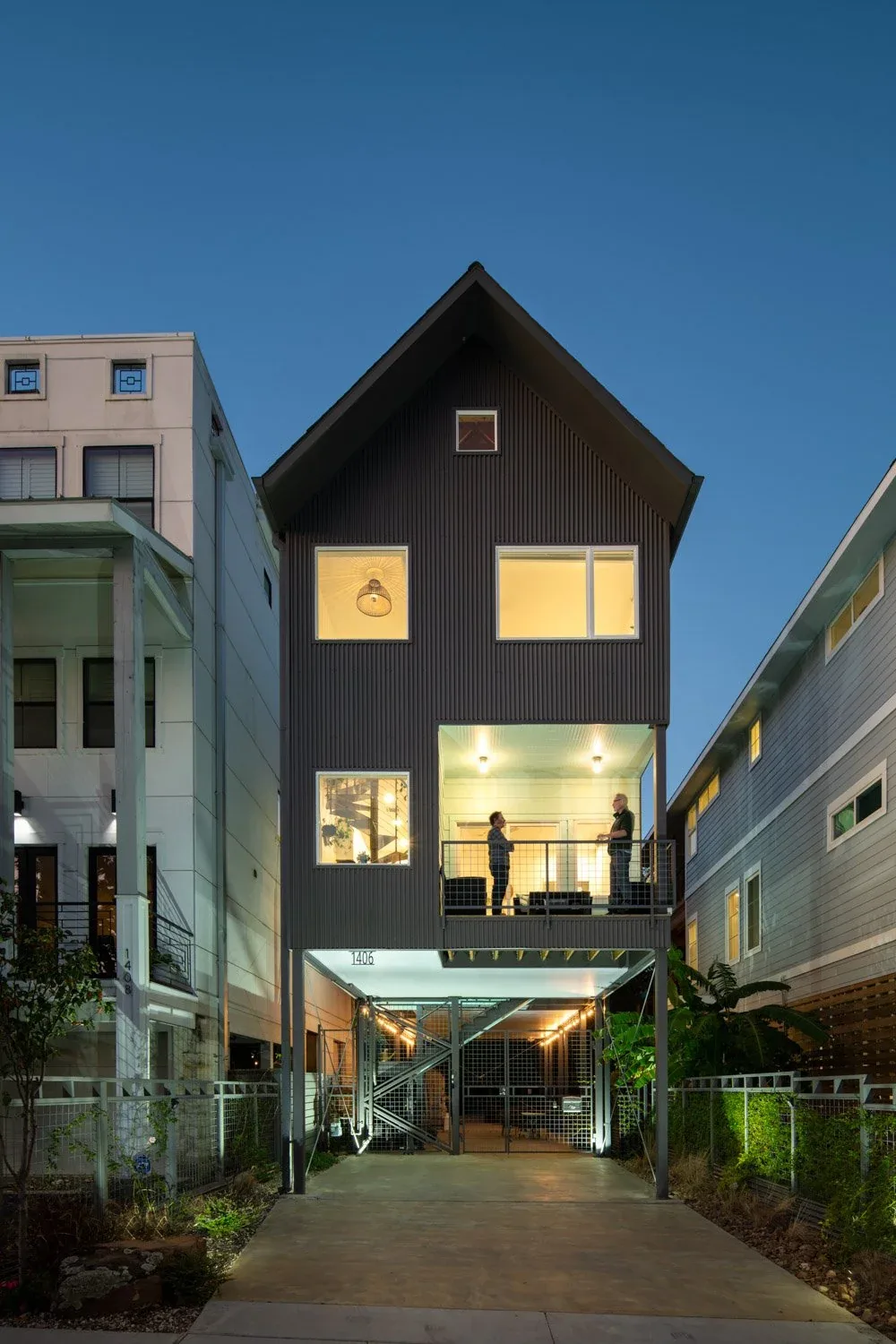 Saunders House is a raised structure with metal siding, an elevated balcony, and urban lot surroundings.